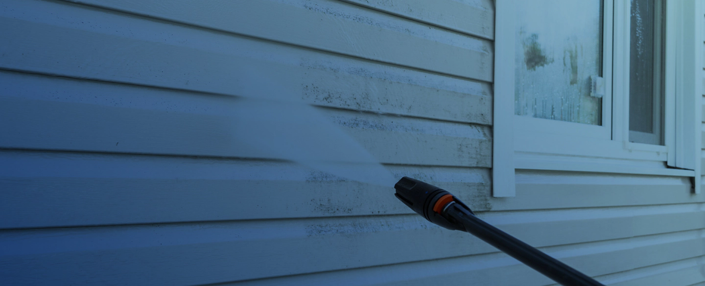 pressure washing machine cleaning a white siding of a house